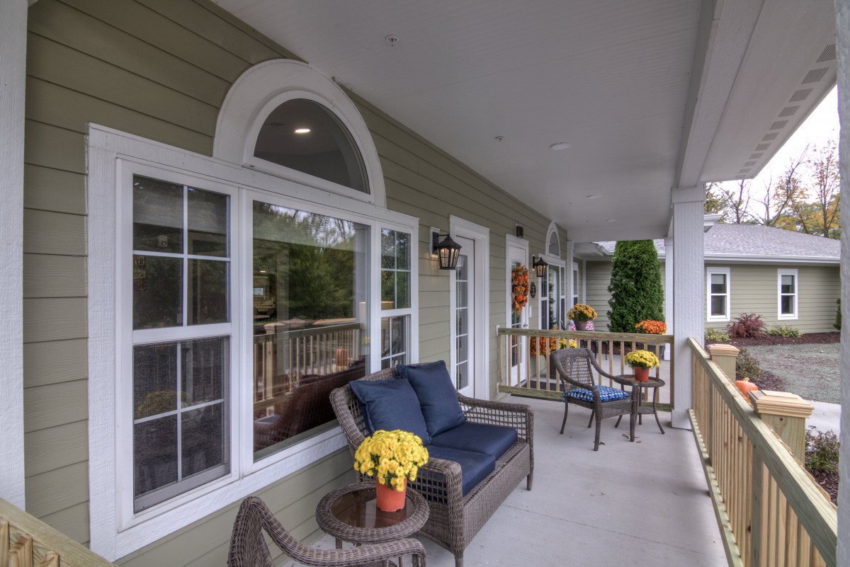A cozy porch with outdoor seating and decorative flowers.