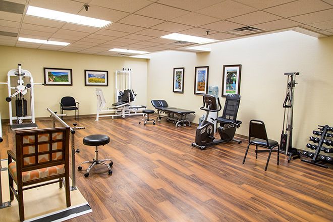 A well-equipped physical therapy room with fitness equipment and chairs.