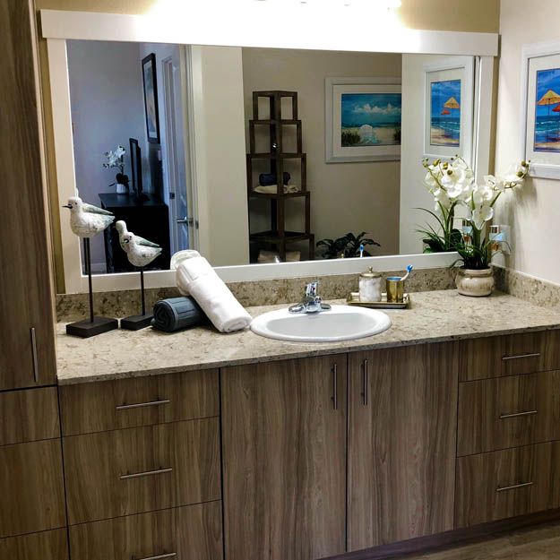 A clean and modern bathroom with a wooden cabinet, large mirror, and elegant decor.