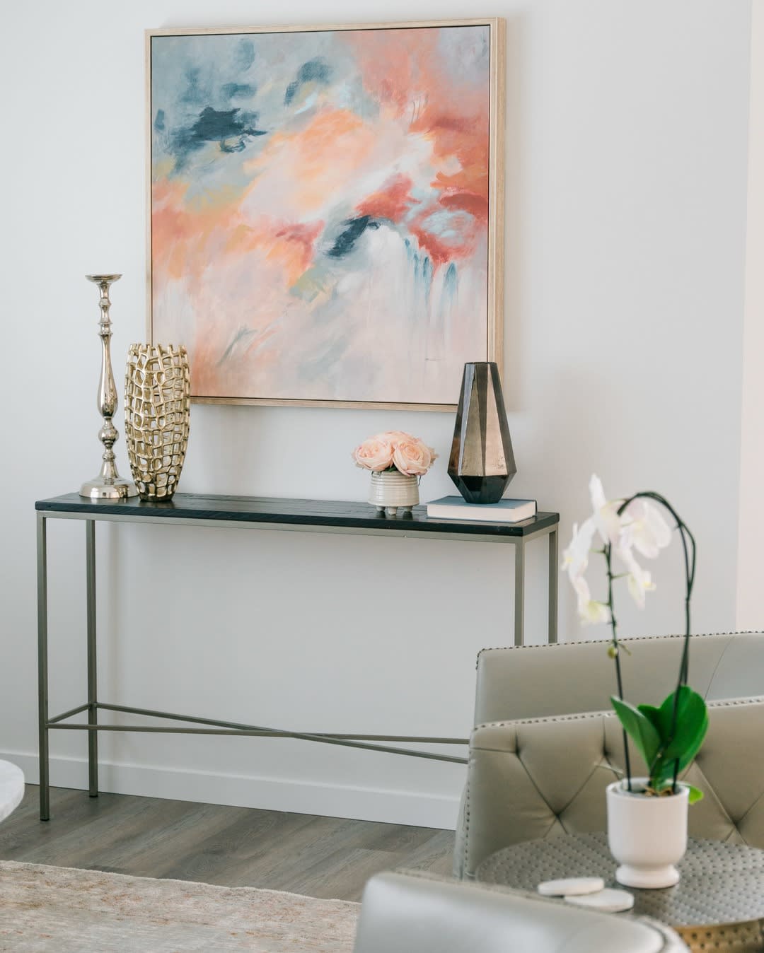 A modern interior with a minimalist console table, abstract artwork, and decorative vases.