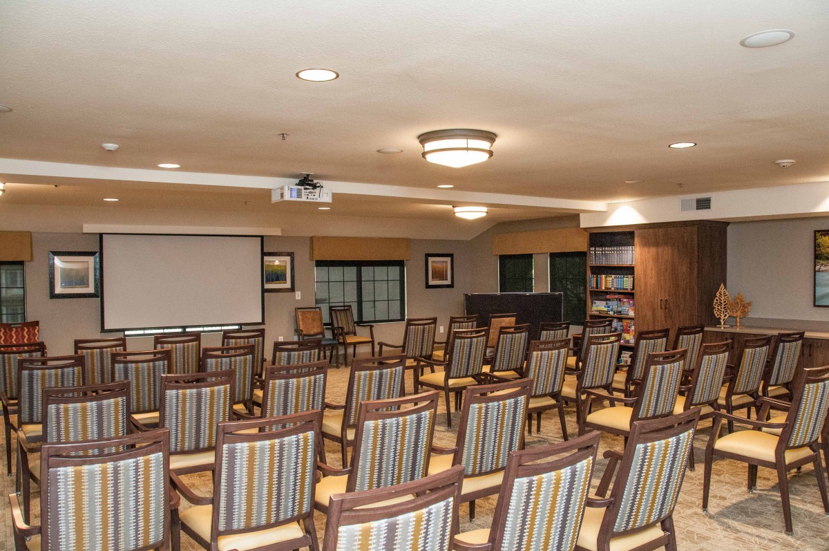 A well-arranged conference room with striped chairs facing a projector screen, ready for a meeting or presentation.