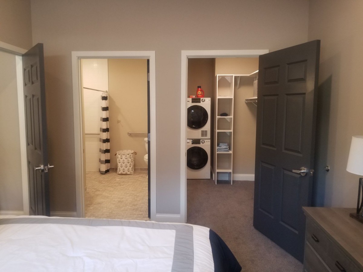 A bedroom view showing an adjacent bathroom and a connected laundry area with a walk-in closet.