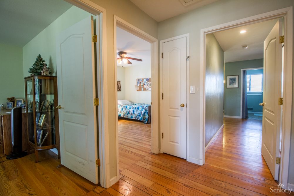 A bright hallway in a home with wooden floors and multiple doors leading to different rooms.