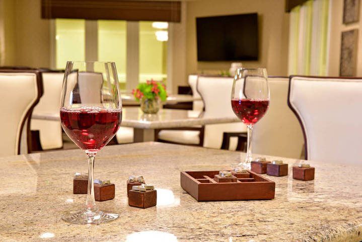 A cozy living room setting featuring glasses of red wine and chocolates on a marble table.