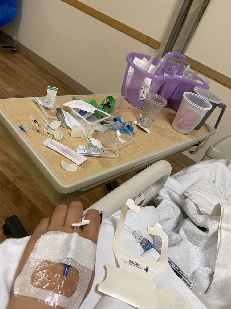 A patient in a hospital bed with medical supplies on a nearby table.