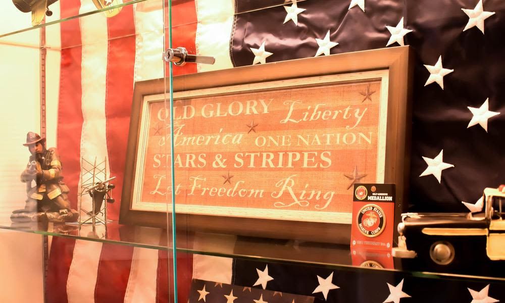 Framed patriotic artwork displayed against an American flag backdrop.