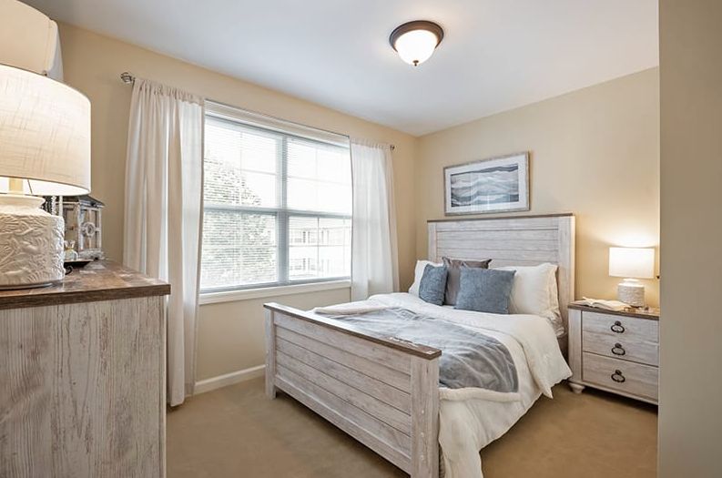 A cozy bedroom with elegant decor, featuring a bed, nightstands, and a large window.