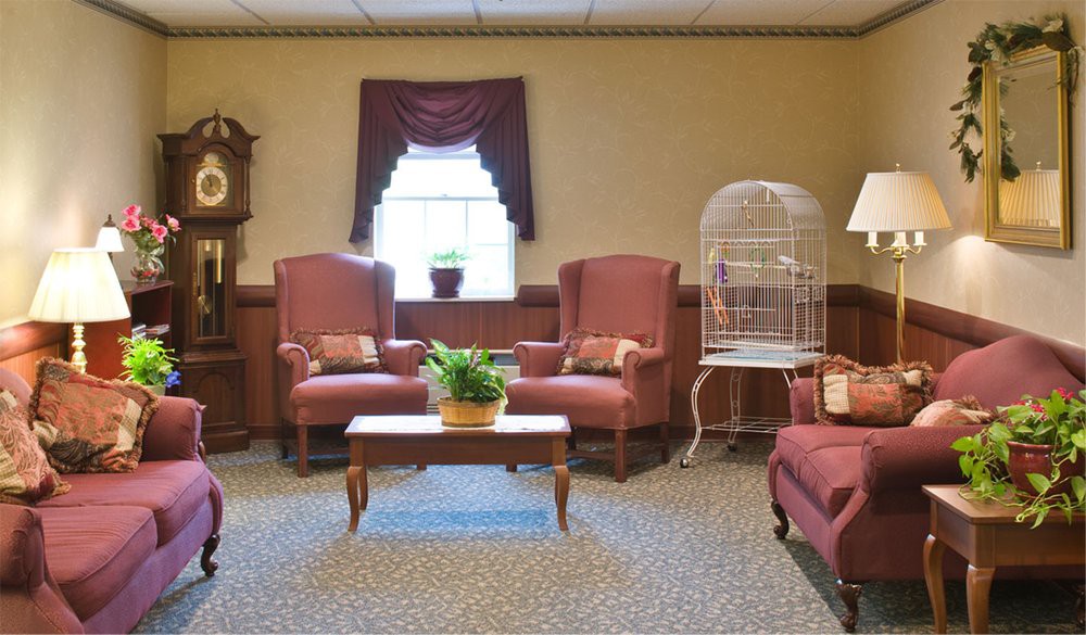 A cozy living room with two armchairs, a coffee table with a plant, and a birdcage by the window.