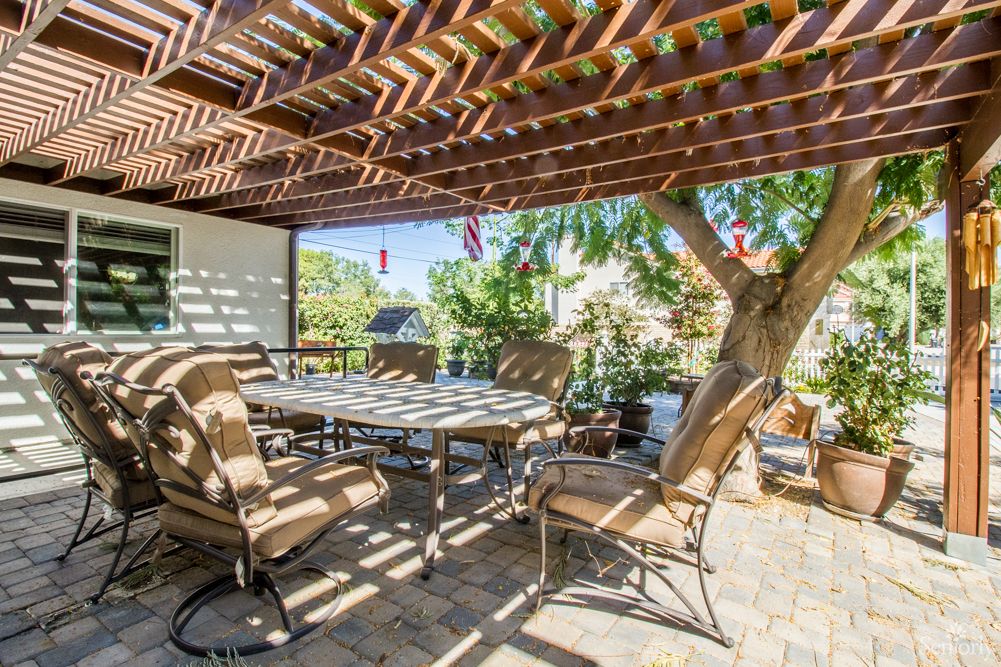 A cozy outdoor patio with chairs and a table under a pergola, providing a shaded area in the backyard.