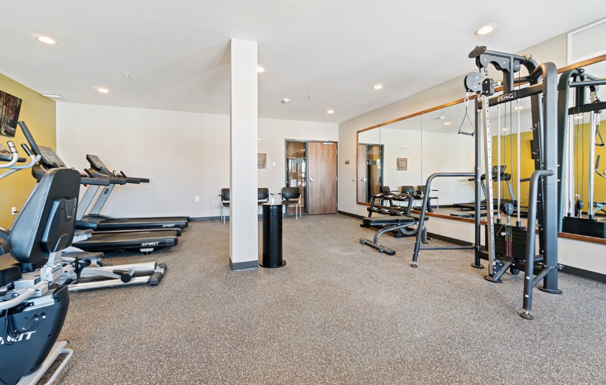 A modern gym with various exercise equipment and large mirrors.