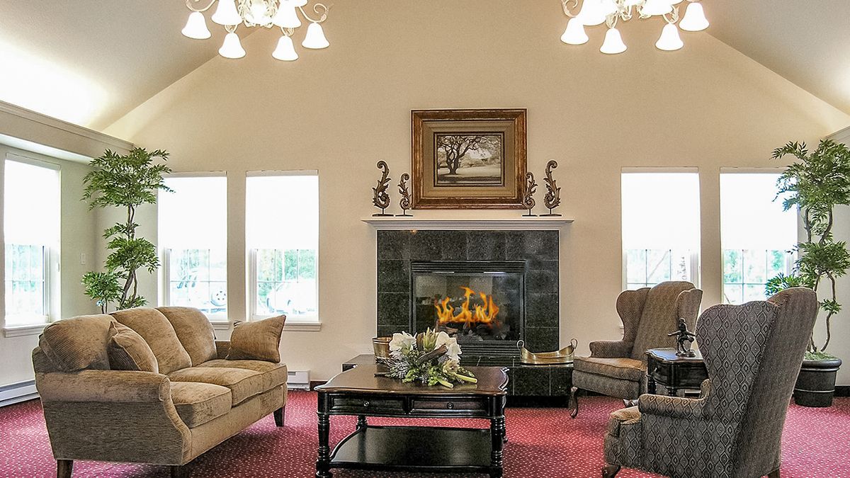 A cozy living room with a fireplace, elegant chandeliers, and comfortable seating.