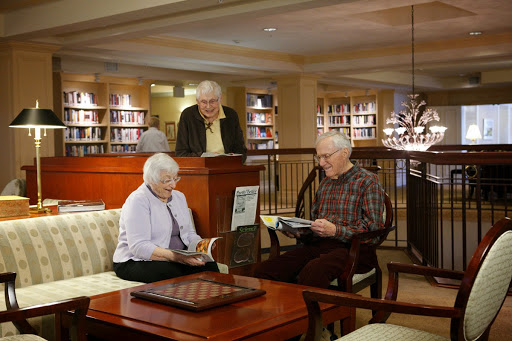 A cozy library setting where seniors enjoy reading and engaging in conversation.