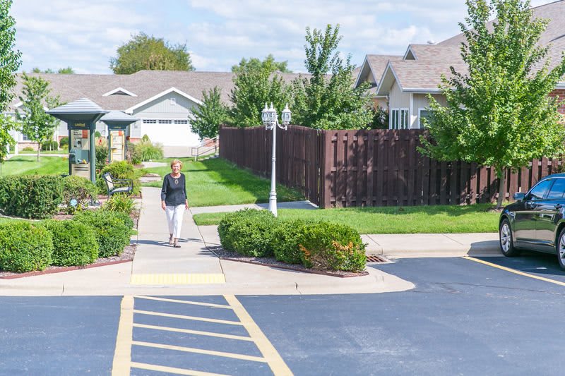 A person walking in a residential neighborhood with houses and greenery.