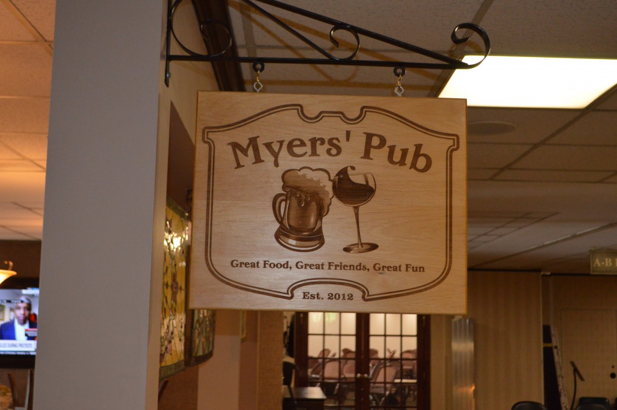 A wooden sign for 'Myers' Pub' featuring illustrations of a beer mug and wine glass.
