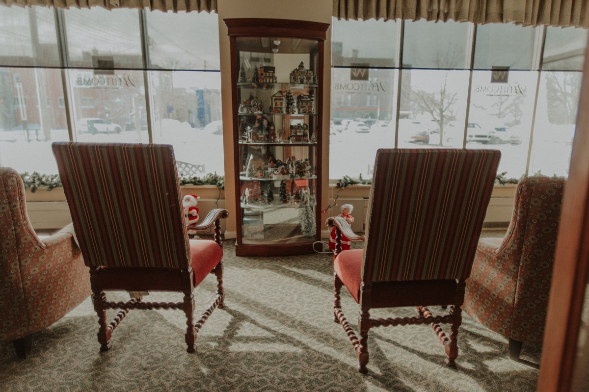 A cozy living room setup featuring two vintage chairs and a display cabinet by a large window.