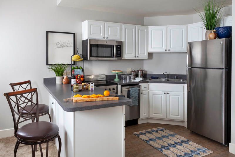 A modern kitchen with white cabinets, stainless steel appliances, and a countertop adorned with fruits.