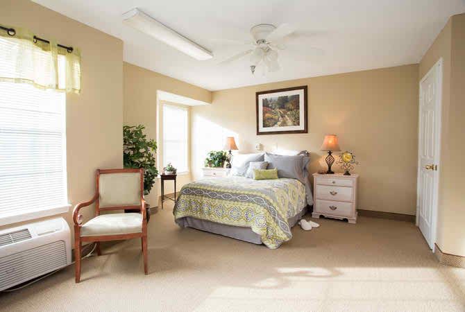 A cozy bedroom with neutral tones, featuring a comfortable bed, nightstand, and elegant chair.