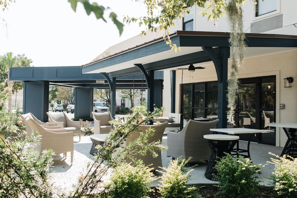 Outdoor patio seating area at a restaurant, featuring tables and chairs under a shaded pergola.