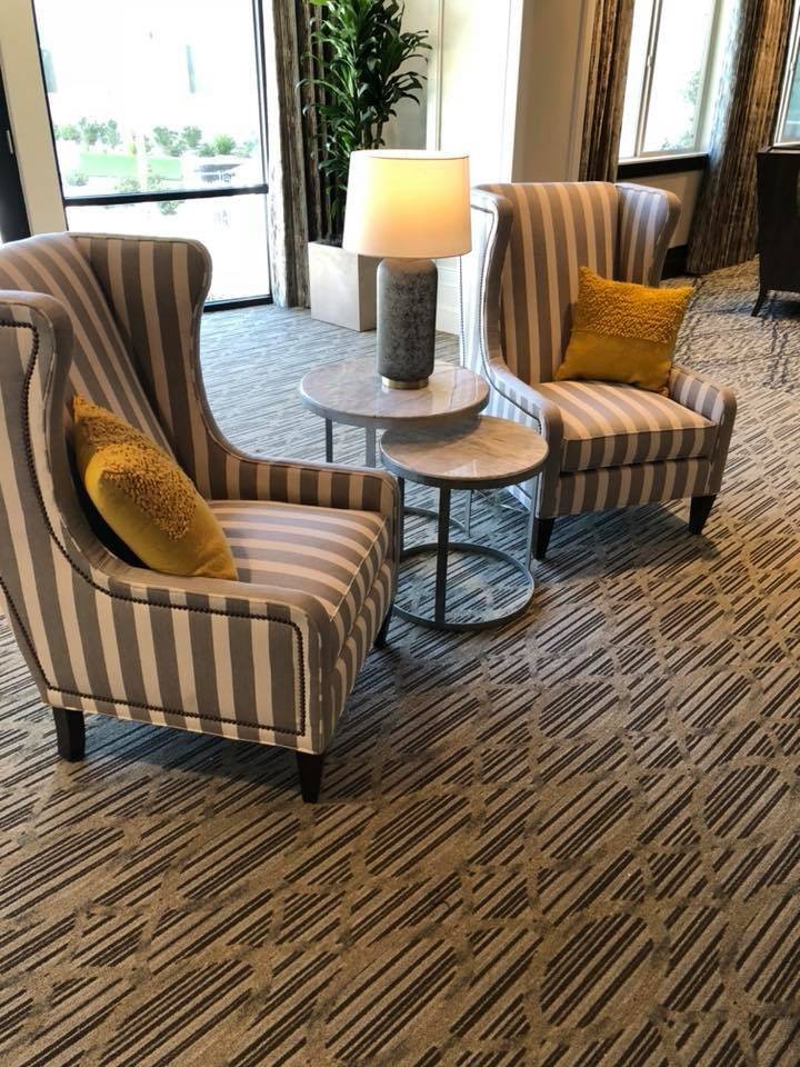 A cozy seating arrangement with striped armchairs, a side table, and a lamp in a lobby.