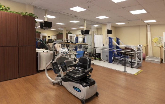 A fitness center with various exercise machines and equipment arranged neatly inside a well-lit room.