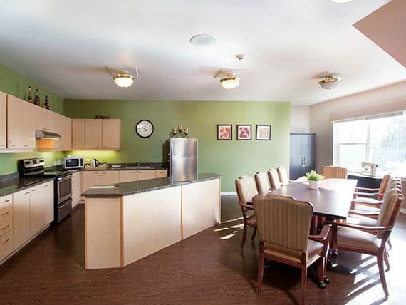 A modern kitchen and dining area with green walls and contemporary furniture.