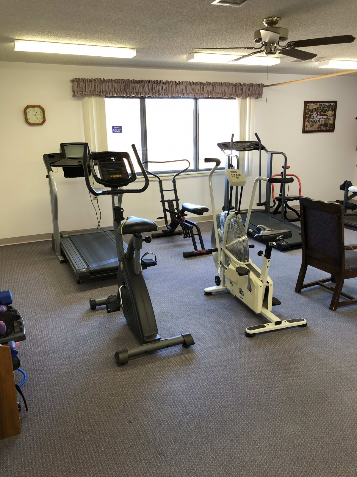 A small indoor gym with various exercise equipment including treadmills and stationary bikes.