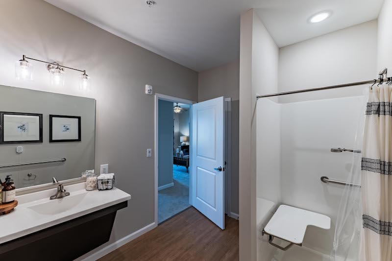 A modern bathroom with a shower and sink, featuring a doorway leading to another room.