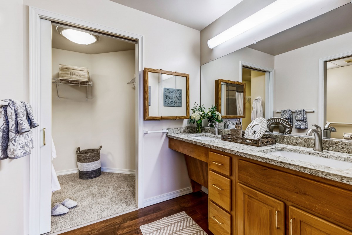 A contemporary bathroom with a wooden vanity, double sinks, and ample lighting.