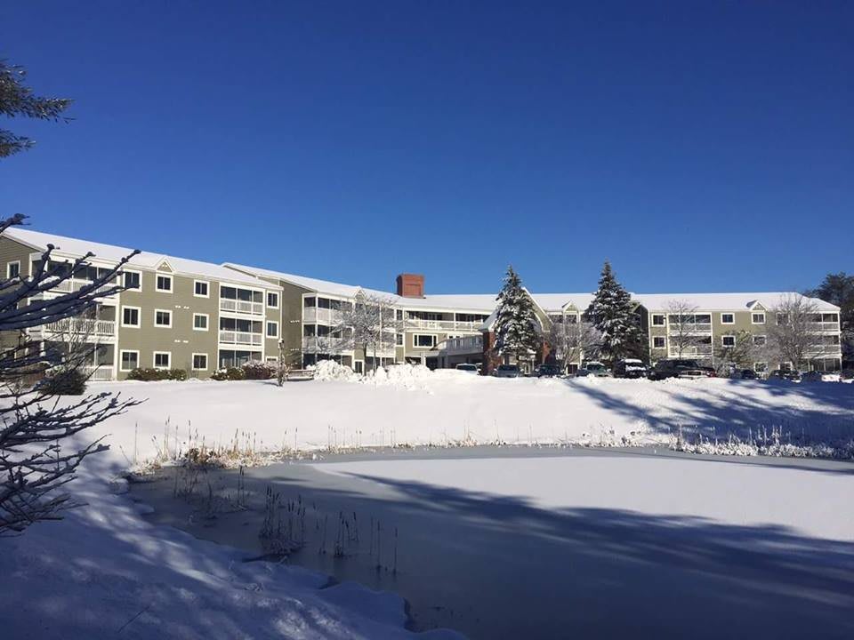 A snowy landscape with a residential building under a clear blue sky.