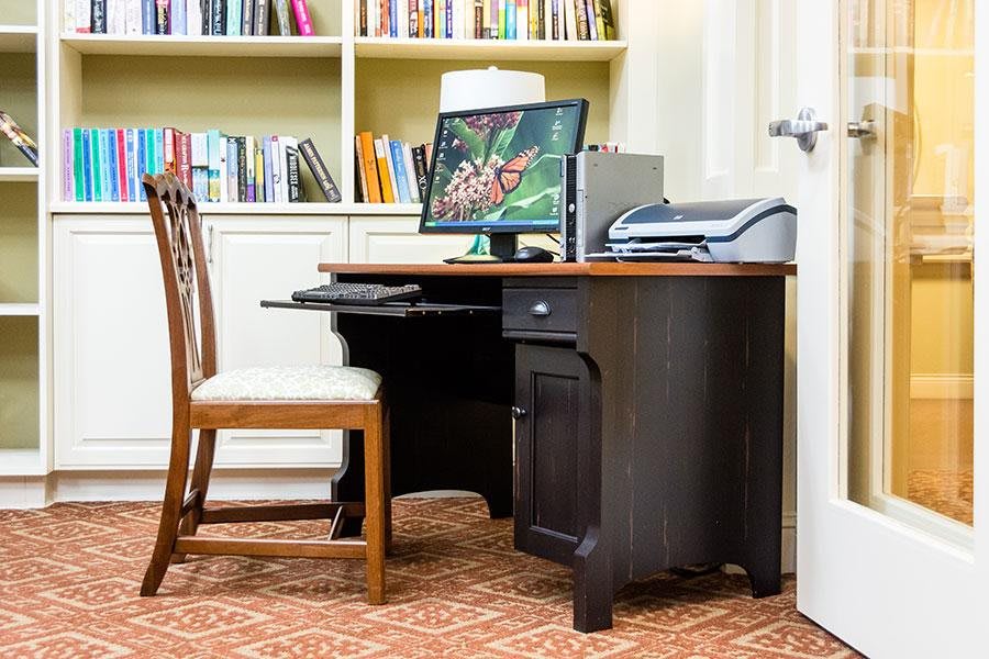A home office setup featuring a desk with a computer, chair, and bookshelf.