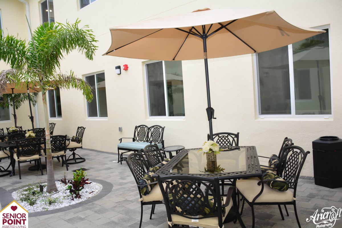 A cozy outdoor patio area with decorative furniture and a large umbrella.