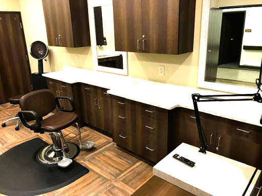 A modern barbershop setup featuring a stylish haircut station with cabinetry and a large mirror.