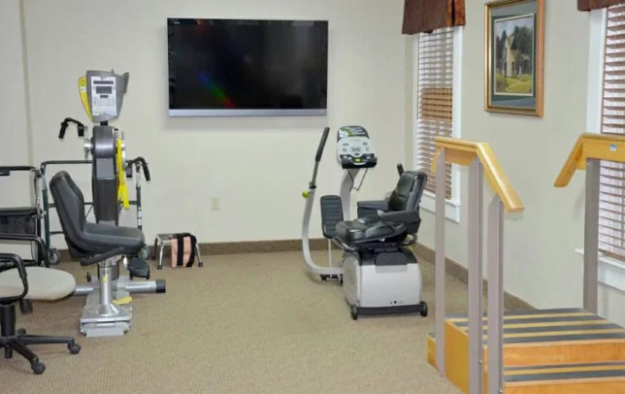 A rehabilitation room equipped with exercise machines and a television.