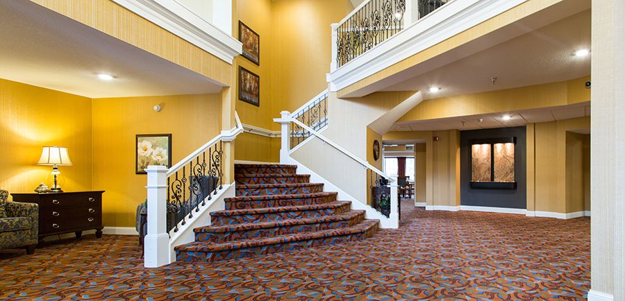 A hotel lobby featuring a grand staircase with patterned carpeting and decorative railings.