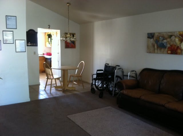 A cozy living room with a dining area and a wheelchair next to a sofa.