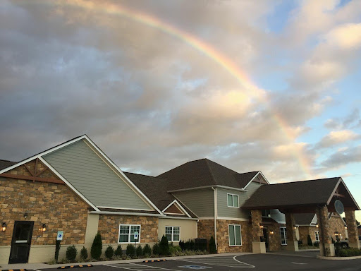 A beautiful rainbow arching over a charming building under a cloudy sky.
