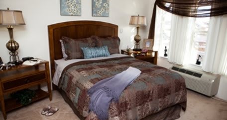 A cozy bedroom with a well-decorated bed, soft pillows, and a bedside lamp.