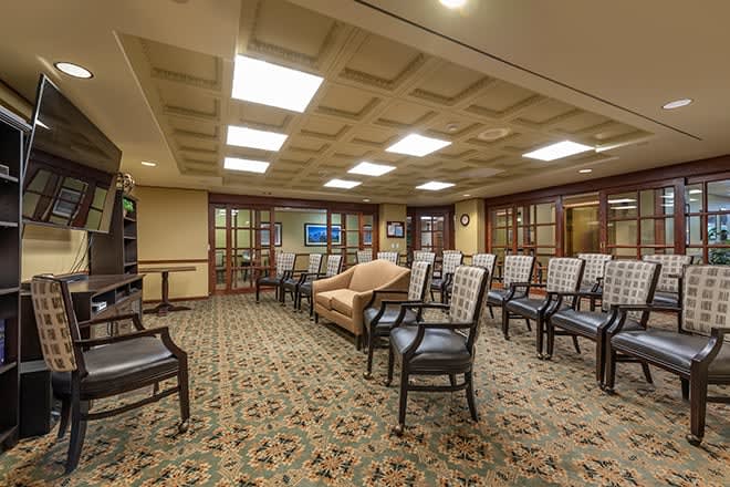 A spacious waiting room with rows of chairs and a carpeted floor.