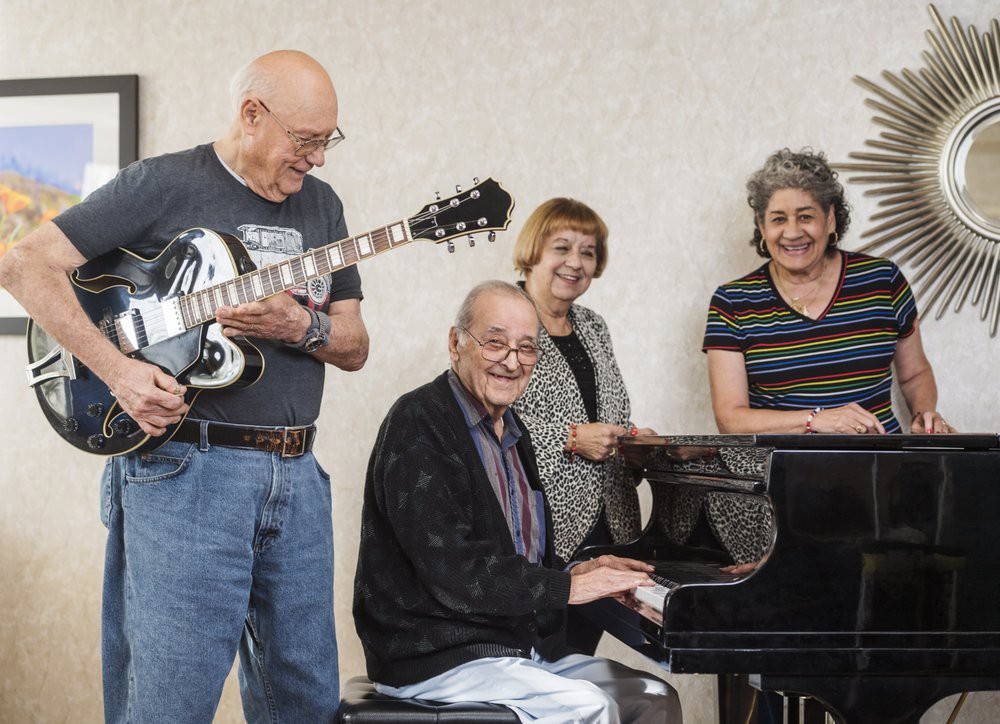 A group of people enjoying music together with a guitar and piano.