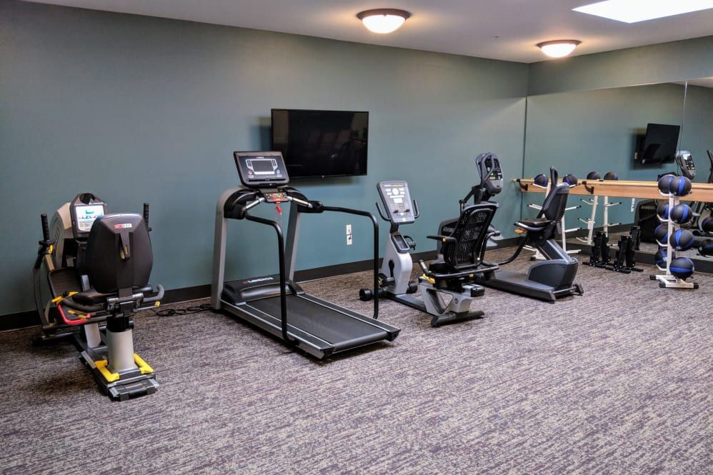 A gym with various exercise equipment including a treadmill and exercise bikes.
