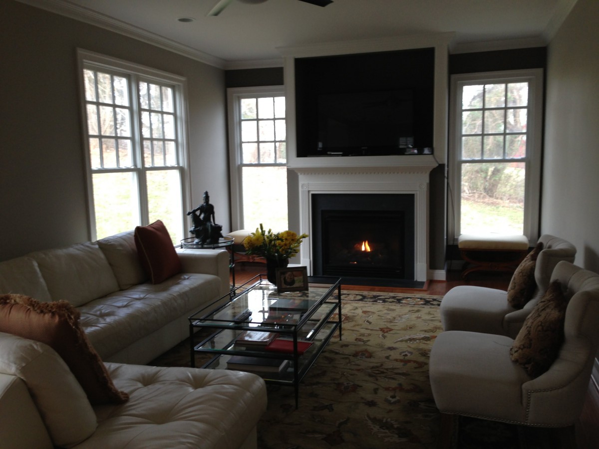 A cozy living room with a fireplace, featuring a comfortable sofa, large windows, and a sleek coffee table.