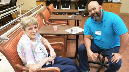 An elderly woman enjoys a moment with a caregiver, sharing smiles and conversation in a cozy indoor setting.