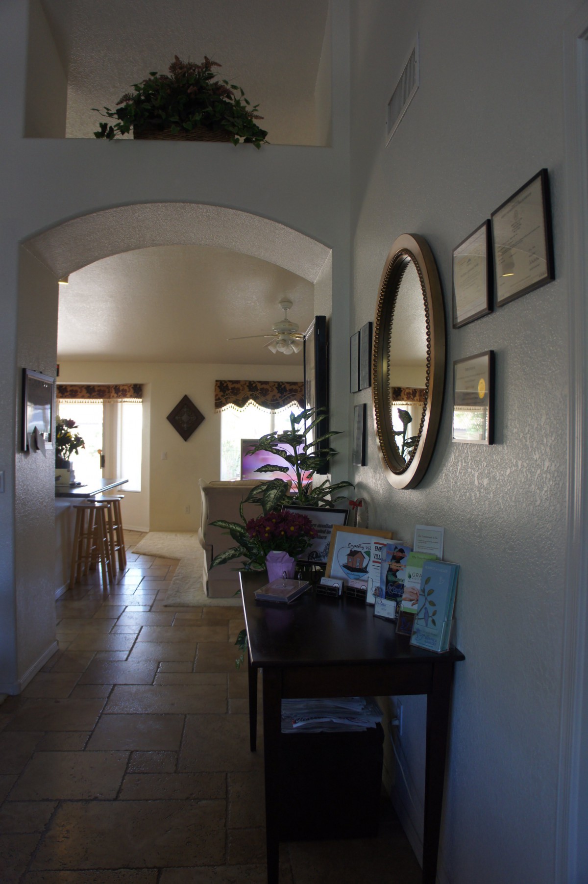 A cozy hallway with a decorative mirror and furniture, leading into a warmly lit living room.