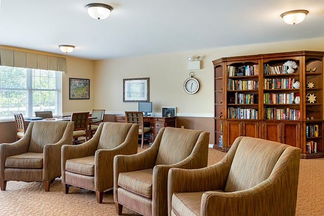 A cozy library room with armchairs, bookshelves, and computers.