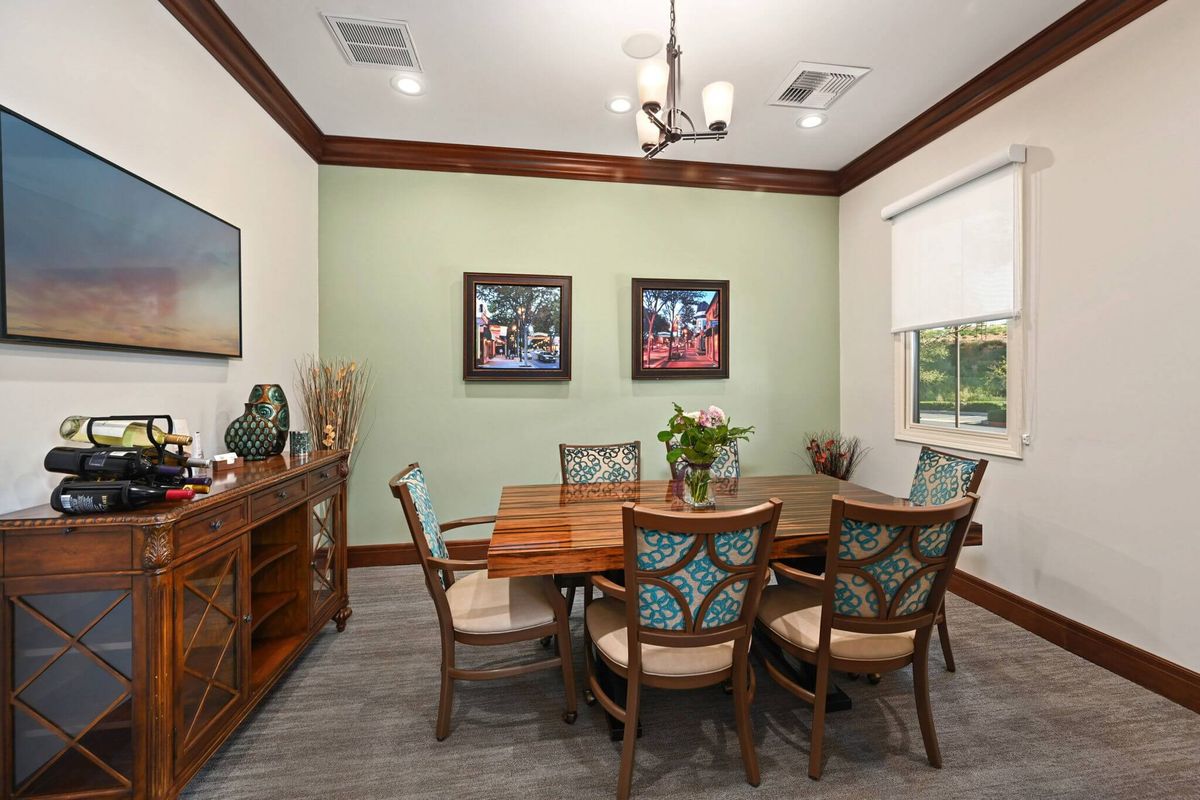 A cozy dining room with wooden furniture, colorful wall art, and a soft green accent wall.