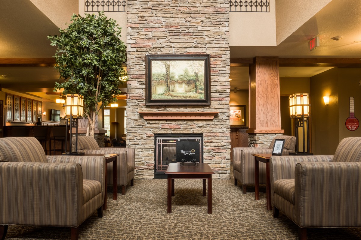 A cozy hotel lobby features comfortable seating and a central fireplace, surrounded by elegant decor.