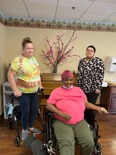 A joyful moment shared among three individuals in a care facility.