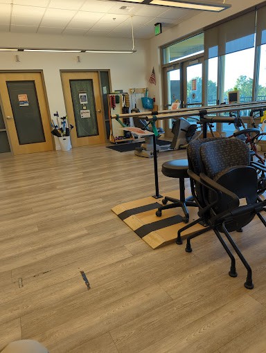A physical therapy room equipped with exercise equipment and parallel bars, designed for rehabilitation exercises.
