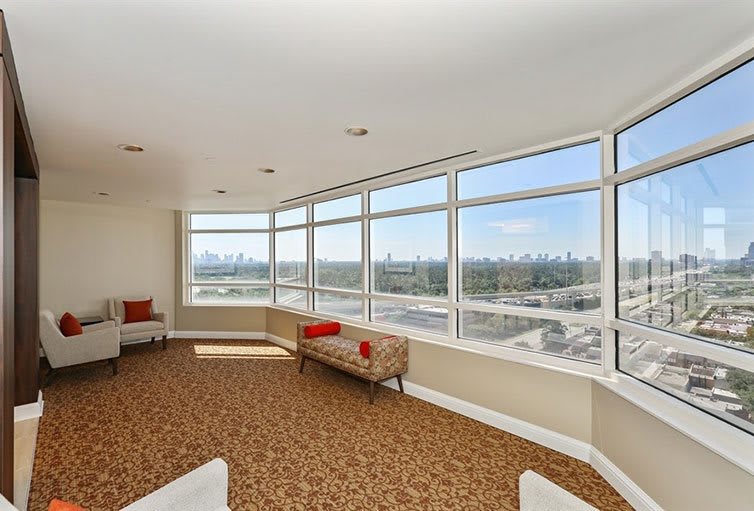A modern penthouse interior with large windows showcasing a city view.