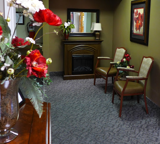 A cozy waiting room featuring comfortable chairs, decorative flowers, and a fireplace.